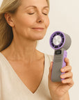 Woman using a portable handheld cooling fan, shown in hand for size reference.