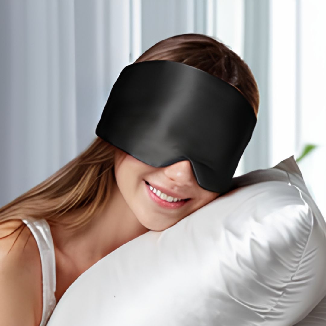 Person wearing a black sleep mask with a white pillow and light background