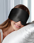 Person wearing a black sleep mask with a white pillow and light background