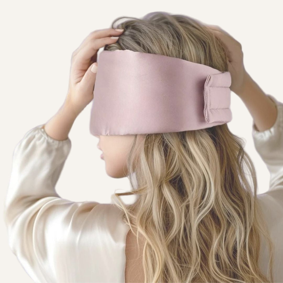 Person wearing a pink silky eye mask against a light background