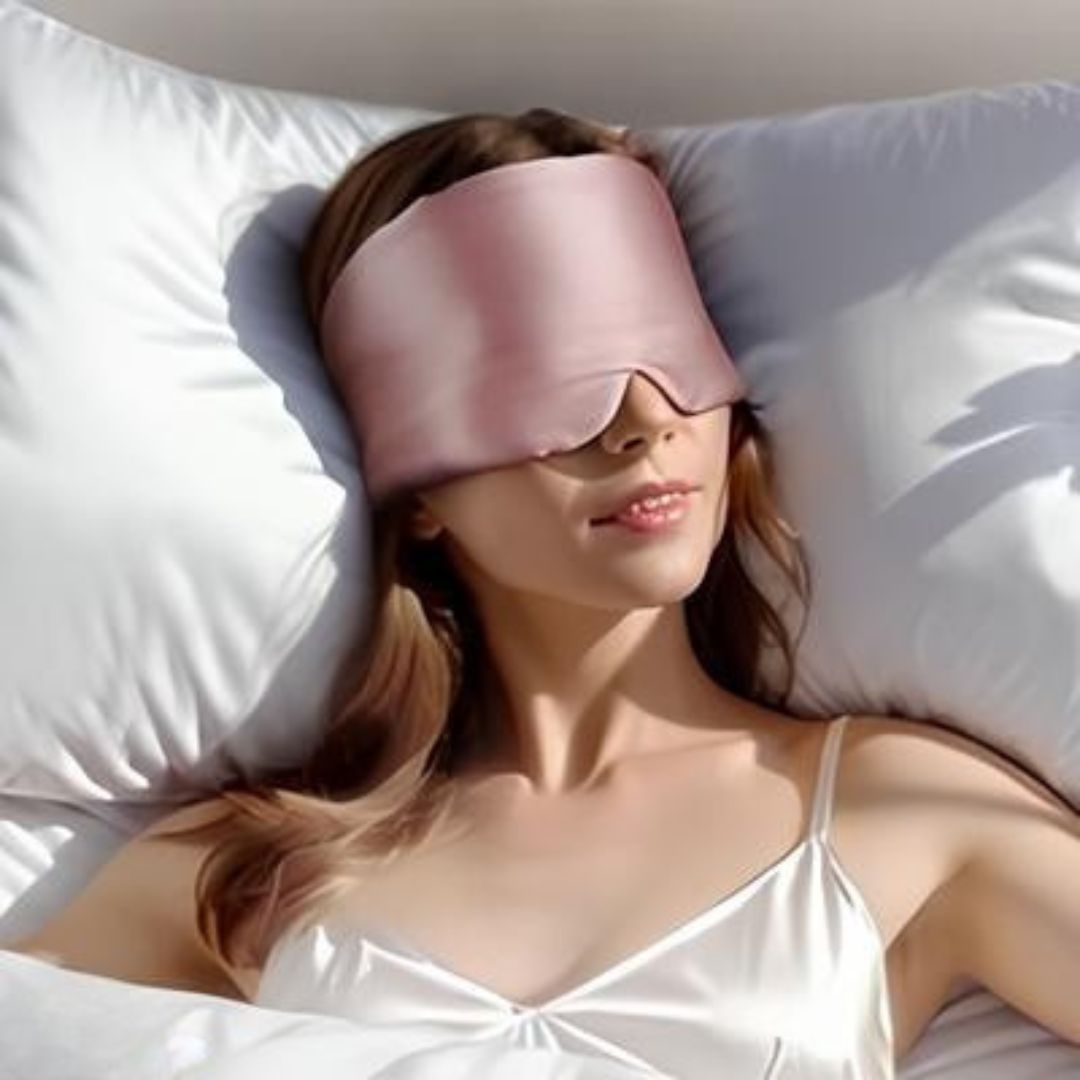 Woman wearing a pink sleep mask lying on white pillow.